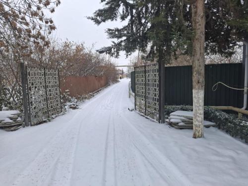 a snow covered road with a fence and a tree at Villa Lux in Quba in Quba