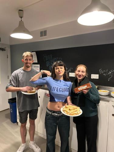 a group of people standing in a kitchen with plates of food at Astor Kensington Hostel in London