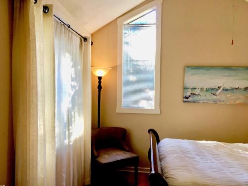 a bedroom with a bed and a window and a chair at Charming Garden Cottage in Eugene