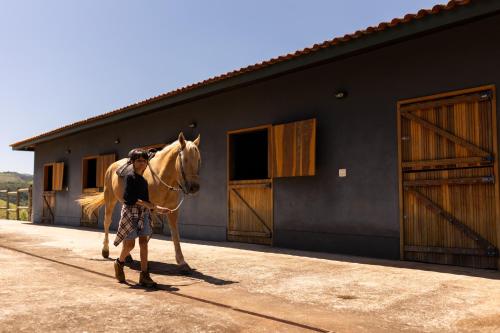 a man holding a horse in front of a building at Pousada Fazenda Aroeira Secretário in Itaipava