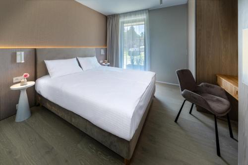 a bedroom with a large bed and a chair at Apartamenty na Półwyspie Wydma&Las in Jastarnia