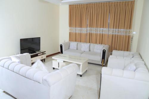 a living room with white couches and a tv at My dream apartment in Addis Ababa