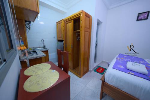 a small bedroom with a bed and a kitchen at Résidence Vinelly in Douala