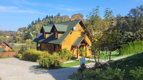 een geel huis met een groen dak bij Malina in Zawóz