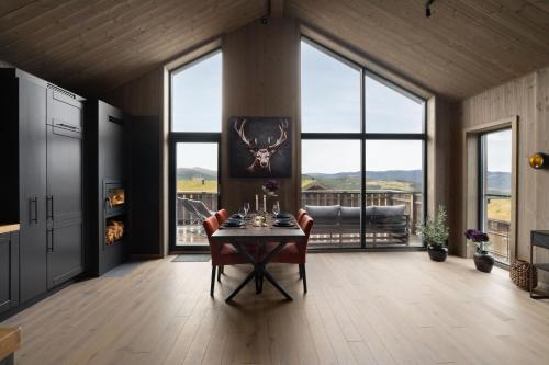 a dining room with a table and chairs and windows at Nesfjellet in Nes i Ådal