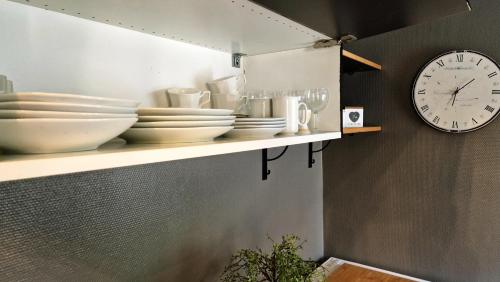 une étagère avec des plaques et une horloge sur un mur dans l'établissement La Canotière - Petite maison pour 2 personnes à Vienne en Arthies, à Villers-en-Arthies