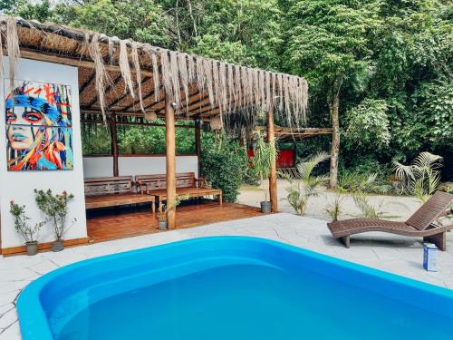a pool in front of a house with a painting at Pousada AimeMaresias - Casa 2 quartos na mata -01 in São Sebastião