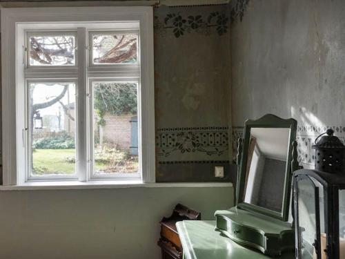a mirror sitting on a table next to a window at Historic Farm House In The Wendland Region in Beesem
