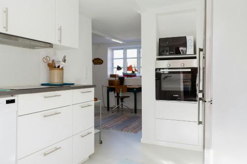 a kitchen with white cabinets and a microwave at The Soulful Town House In The Heart Of Faaborg in Fåborg