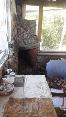 a stone fireplace in a living room with a table at cabaña sin luz en campo in San Carlos