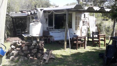 a caravan with an umbrella and chairs in a yard at cabaña sin luz en campo in San Carlos