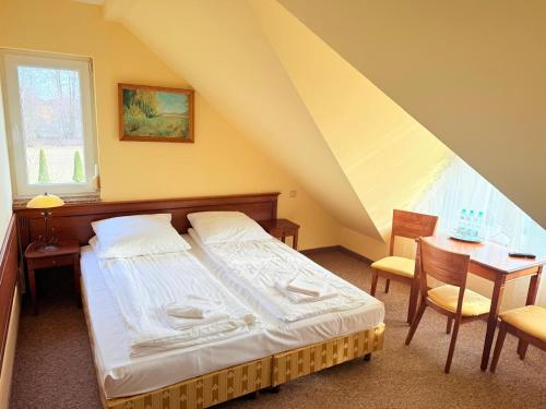 a bedroom with a bed and a table and a window at Pokoje noclegowe KASZTEL - Łowisko in Łowisko
