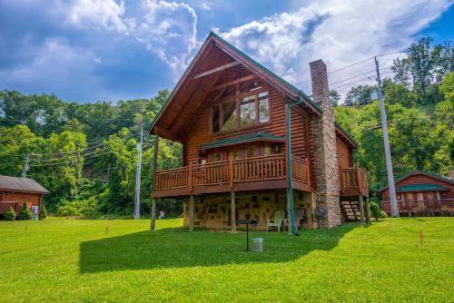 a log cabin with a deck on a green field at River Cabin in Pigeon Forge