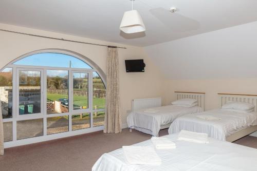two beds in a room with a large window at Whittonlodge sleeps28 Hottub pool table in Hardstoft