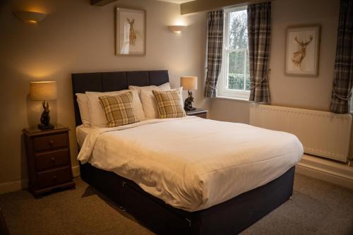 a bedroom with a large bed with white sheets and pillows at Anglers Arms in Alnwick
