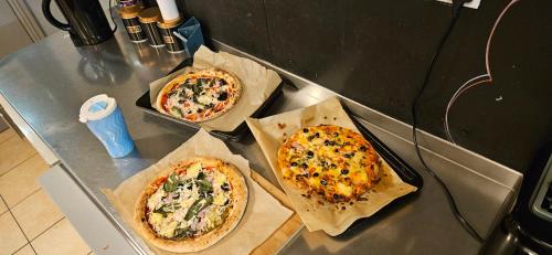 three pizzas sitting on top of a counter at Astor Victoria Hostel in London