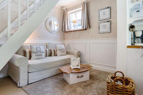 a living room with a white couch and a table at GÄSTEWOHNUNGEN AM SEE "Maisonette & Suite" in Neuenkirchen