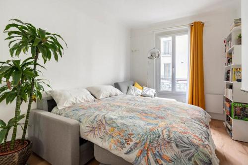 une chambre avec un lit et une plante en pot dans l'établissement Nice and cozy parisian apartment, à Paris