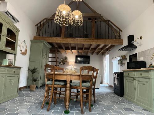 une cuisine avec une table et des chaises ainsi qu'un lustre dans l'établissement La grange cottage d hôte, à Landrecies