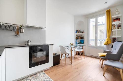 une cuisine avec une cuisinière et une table avec des chaises dans l'établissement Nice and cozy parisian apartment, à Paris