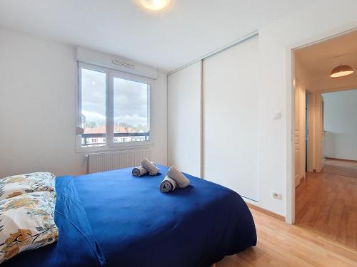 a bedroom with a blue bed with towels on it at Lingo104 - Confort - Proche centre ville - Transports en communs in Lingolsheim