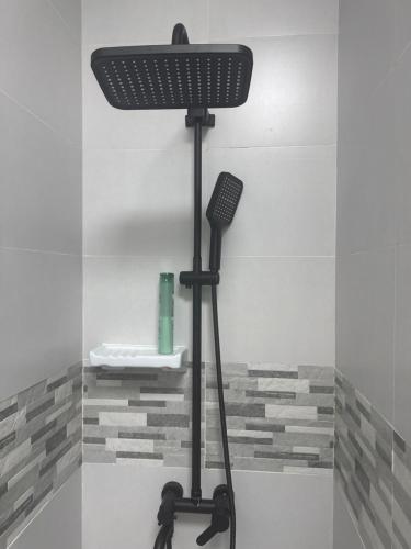 a black shower head on a stand in a bathroom at Homestay Cozy bedroom with private attached washroom in ajman villa in Ajman
