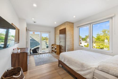 une chambre avec un grand lit et de grandes fenêtres dans l'établissement Luxury 5BR Smart Home Near JFK with Gym, Theater & BBQ, à Valley Stream