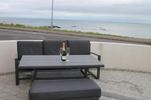 a picnic table with a bottle and a wine glass at Beach View, Portballintrae in Portballintrae