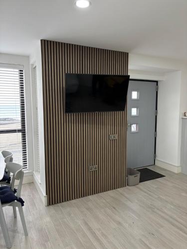 a living room with a television on a wall at Beach View, Portballintrae in Portballintrae