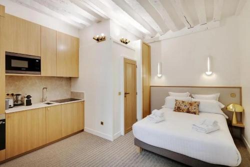 une chambre avec un grand lit blanc et une cuisine dans l'établissement Makom Saint Honore, à Paris