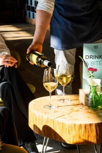 a person pouring wine into two glasses on a table at Hotel Villa Ruimzicht in Doetinchem