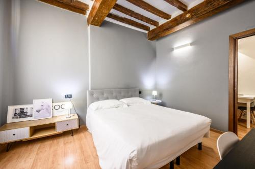 Un dormitorio con una cama blanca y una mesa. en Emilia Studios 3, en Módena