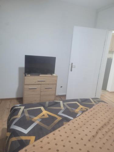 a bedroom with a bed and a dresser and a television at Golden Apartment in Valjevo