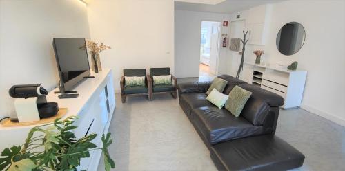 Una sala de estar con un sofá de cuero negro y un televisor. en Caires Urban Nest, en Braga