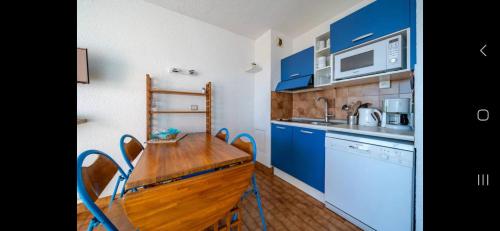 une cuisine avec des placards bleus et une table en bois dans l'établissement Dernier étage vue mer exceptionnelle, à Roquebrune-Cap-Martin