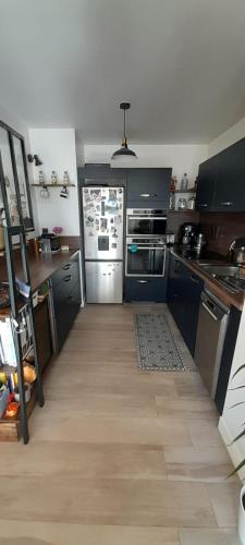 - une cuisine avec des armoires noires et un réfrigérateur blanc dans l'établissement Le Grand Cocon, à La Ciotat