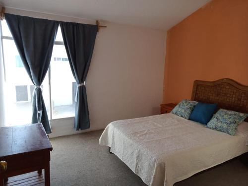 a bedroom with a bed with blue pillows and a window at Fresnos 14 Queretaro in Mendiola