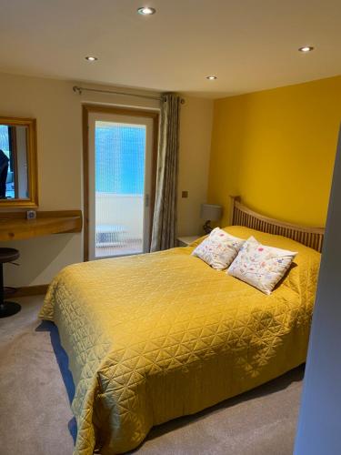 a bedroom with a large yellow bed with two pillows at Otters End, near Wroxham in Dilham