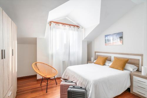 a bedroom with a bed with a chair and luggage at Apartamentos Alday in Maliaño