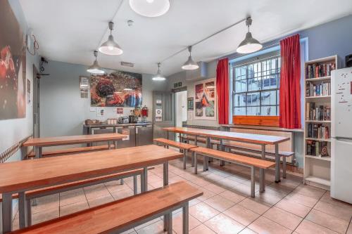a restaurant with benches and tables in a room at Astor Victoria Hostel in London