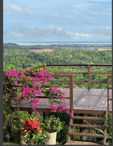 a wooden bench with pink flowers and a view at Chalé da Lourdes in Santarém