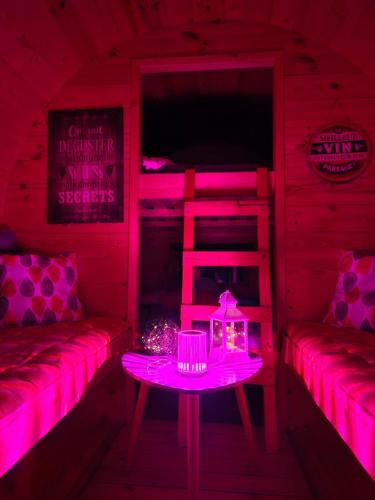 a room with pink lighting and a table and a bunk bed at Les Atypiques de Sologne in Lanthenay