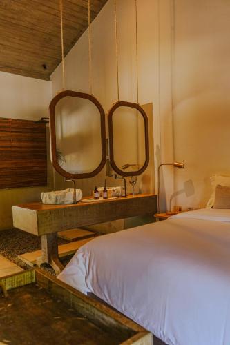 a bedroom with a bed and two mirrors on the wall at Anacardier Privé Hotel in Atins