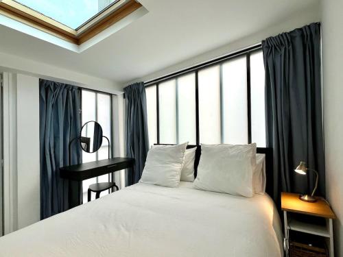 a bedroom with a white bed and a window at Maison duplex, 2 chambres, terrasse en rooftop in Saint-Ouen