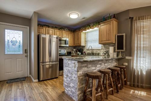 a kitchen with a counter with stools and a refrigerator at Striking Waters in Pigeon Forge