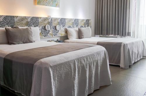 two beds in a hotel room with white sheets at Hotel Punta Azul in Veracruz