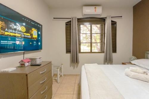 a bedroom with a bed and a tv and a window at Apartamento Bem Localizado na Cerro Azul in Maringá