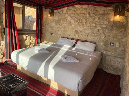 a bedroom with a bed in a stone wall at Dana Trail Hotel in Dana