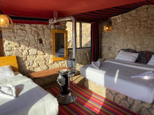 a bedroom with two beds and a stone wall at Dana Trail Hotel in Dana