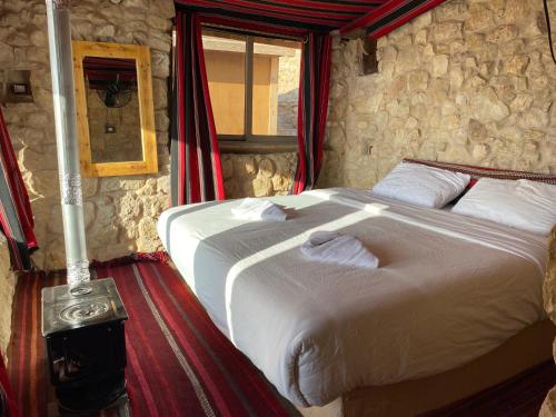 a bedroom with a large bed in a stone wall at Dana Trail Hotel in Dana
